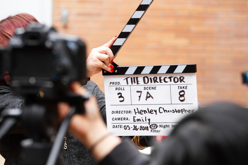 A person who used entertainment director resume examples as a guide holding a production clapper
