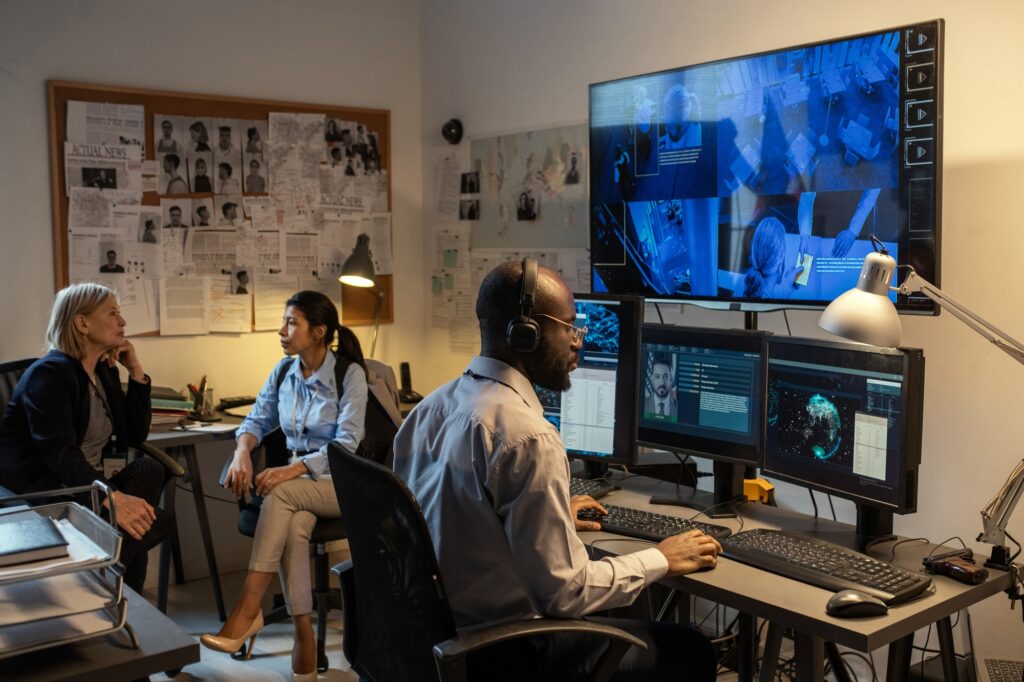 African American FBI agent sitting in front of computer monitors and screen