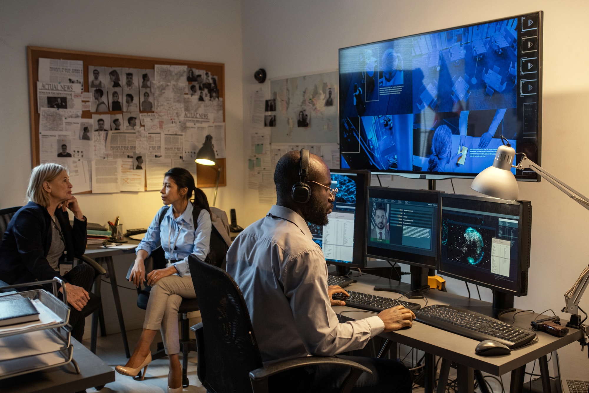 African American FBI agent sitting in front of computer monitors and screen