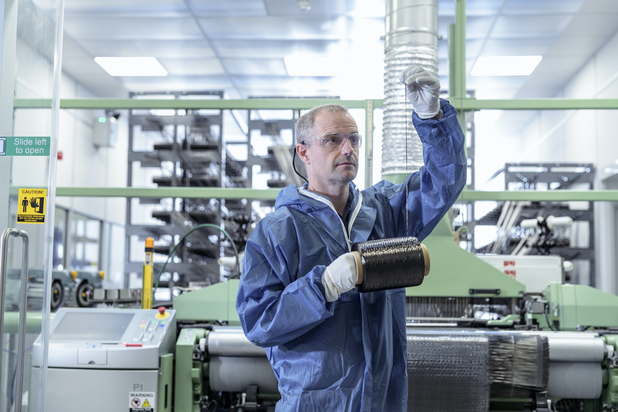 Operator with bobbin of carbon fibre in carbon fibre production facility