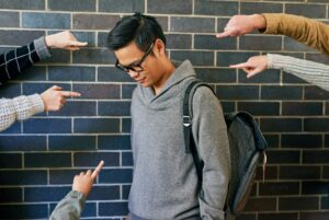 Cropped shot of a young male university student being bullied while standing in a campus corridor